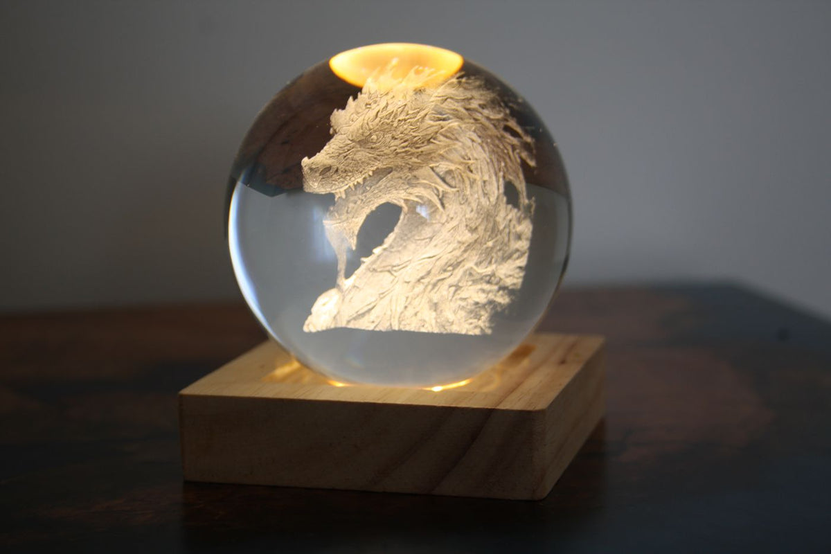 Dragon engraved inside a crystal sphere on a wooden LED base
