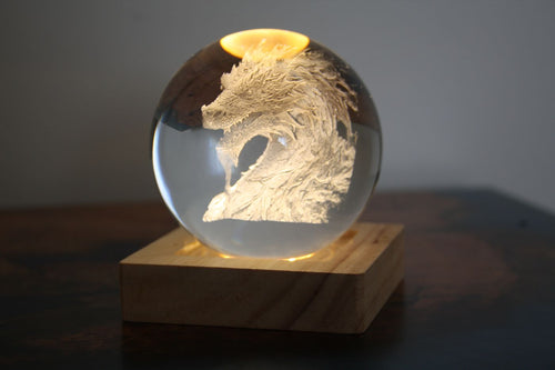 Dragon engraved inside a crystal sphere on a wooden LED base